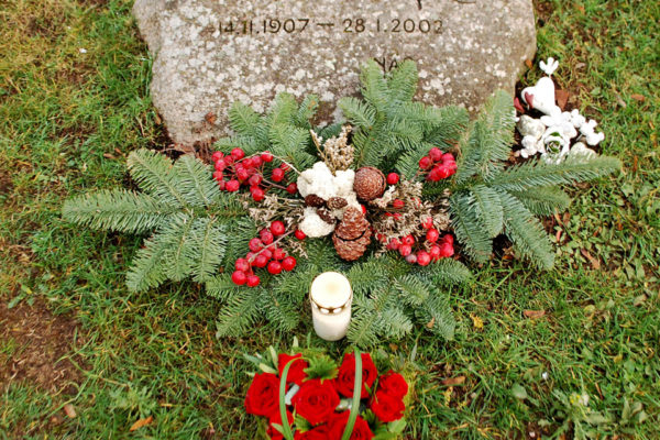 Astrid Lindgrens gravsten dekorerat med granris, röda bär, kottar och ett hjärta gjort av rosor.