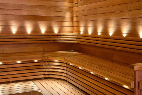 Ett modernt basturum med träpaneler och integrerad LED-belysning under bänkarna och på väggarna.