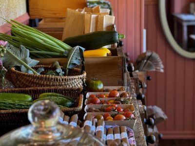 Färska grönsaker och förpackade varor visas på ett träbord i en gårdsbutik.