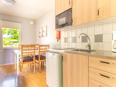 Ett litet kök med träskåp, matplats och utsikt mot grönområde.