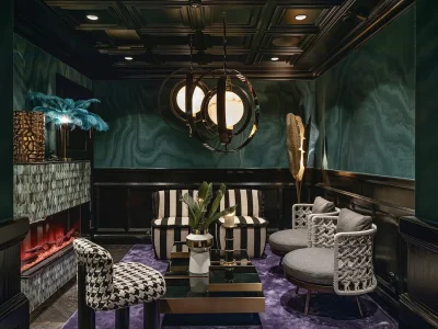 En lyxig, mysig lounge i Vimmerby med mörkgröna väggar, träpaneler, blandade möbler, ett soffbord på lila matta och kassettmålat tak.